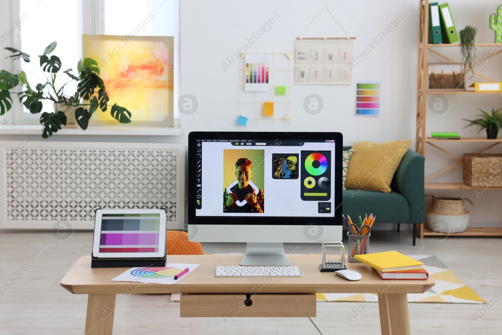 Photo of Designer's workplace with computer, tablet, color palette and stationery on wooden table indoors