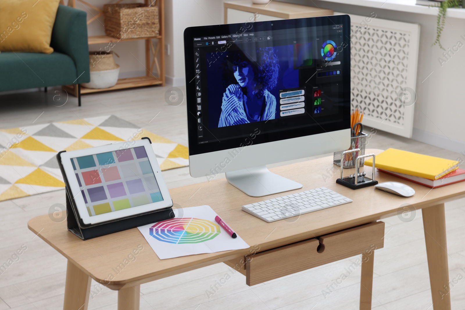 Photo of Designer's workplace with computer, tablet, color palette and stationery on wooden table indoors