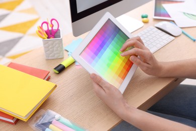 Photo of Designer working on tablet at wooden table indoors, closeup