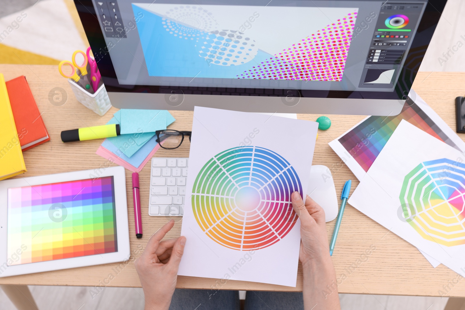 Photo of Designer with color palette working at wooden table indoors, top view