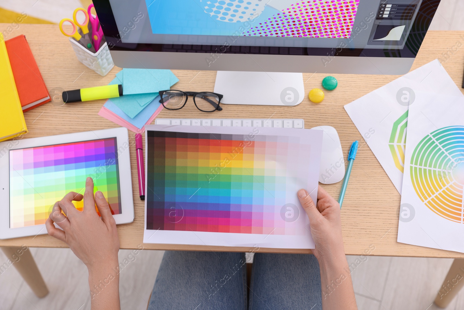 Photo of Designer with color palette working on tablet at wooden table indoors, top view