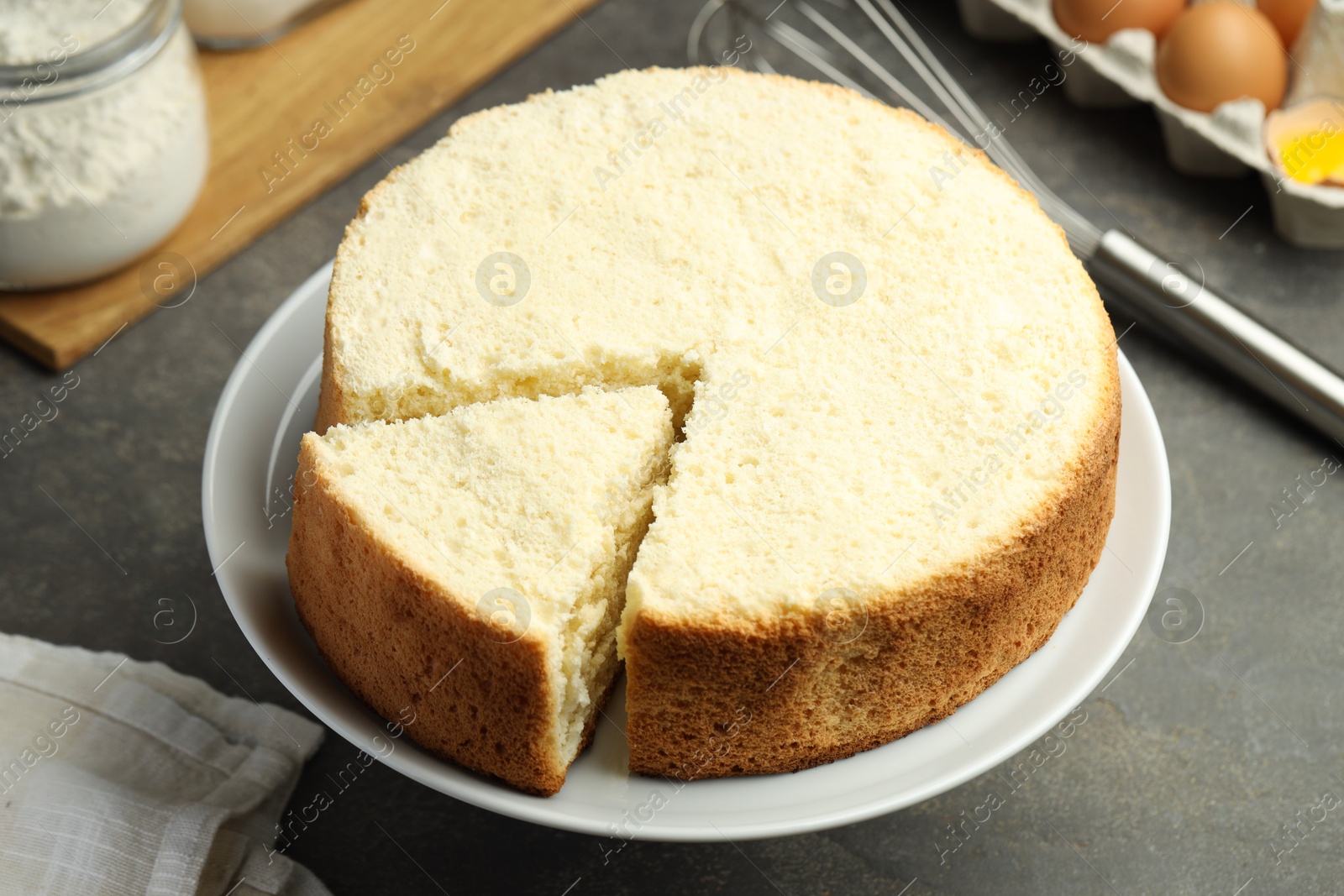 Photo of Tasty cut sponge cake on grey table