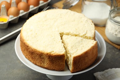 Photo of Tasty cut sponge cake on grey table