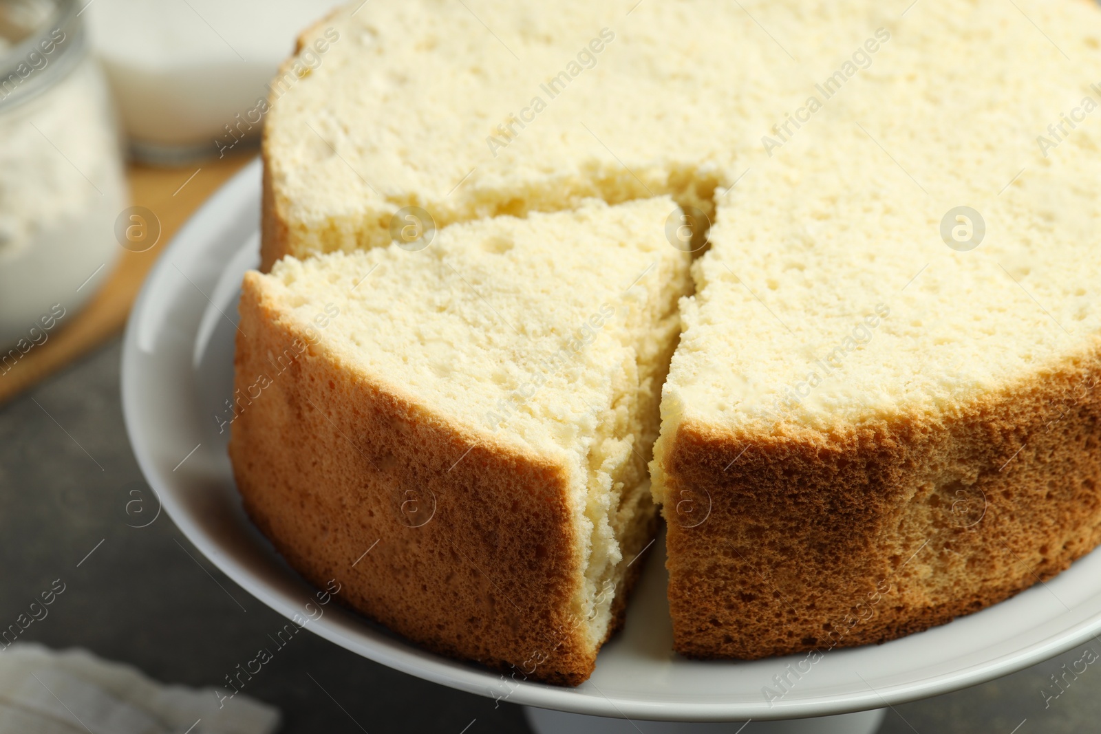 Photo of Tasty cut sponge cake on grey table, closeup