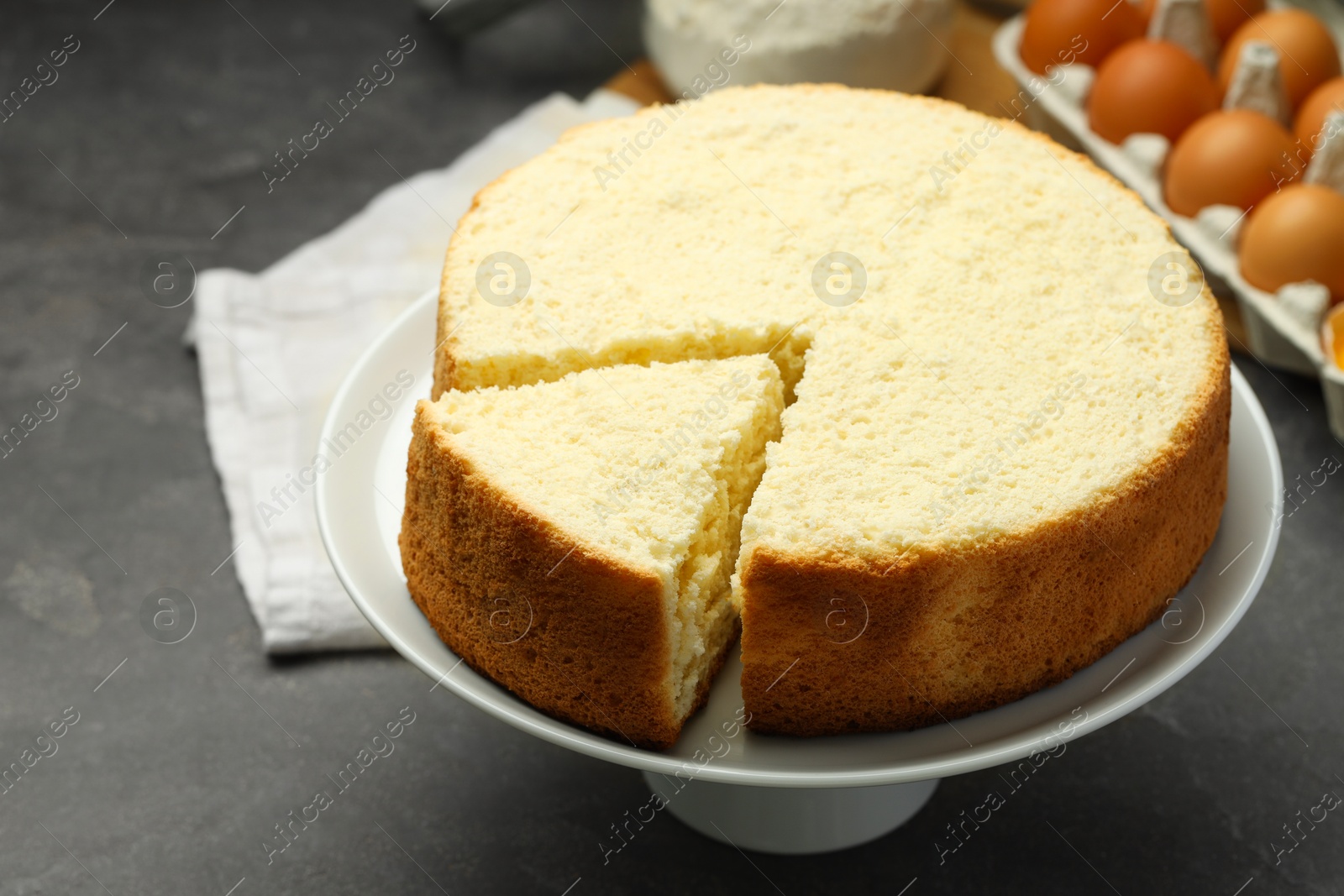 Photo of Tasty cut sponge cake on grey table, closeup