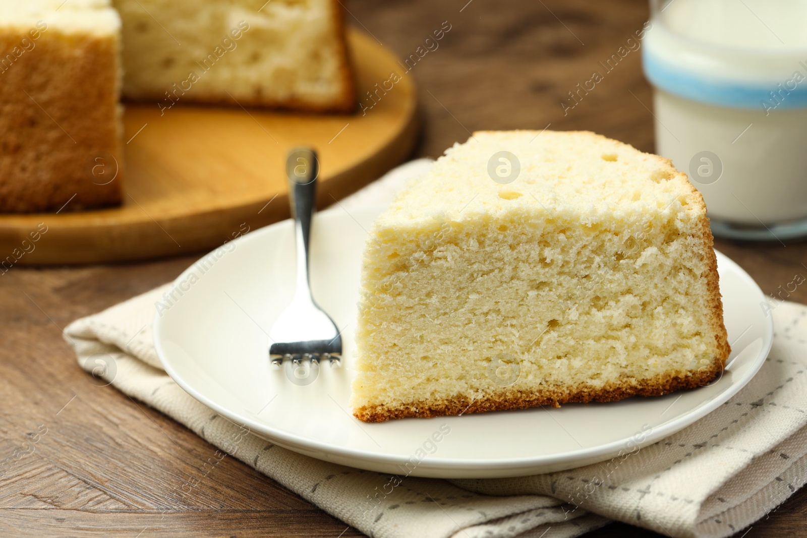 Photo of Piece of delicious sponge cake and fork on wooden table, closeup