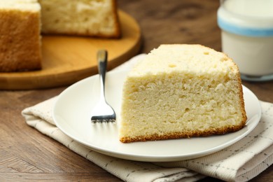 Photo of Piece of delicious sponge cake and fork on wooden table, closeup