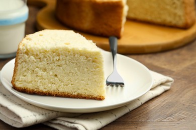 Photo of Piece of delicious sponge cake and fork on wooden table, closeup