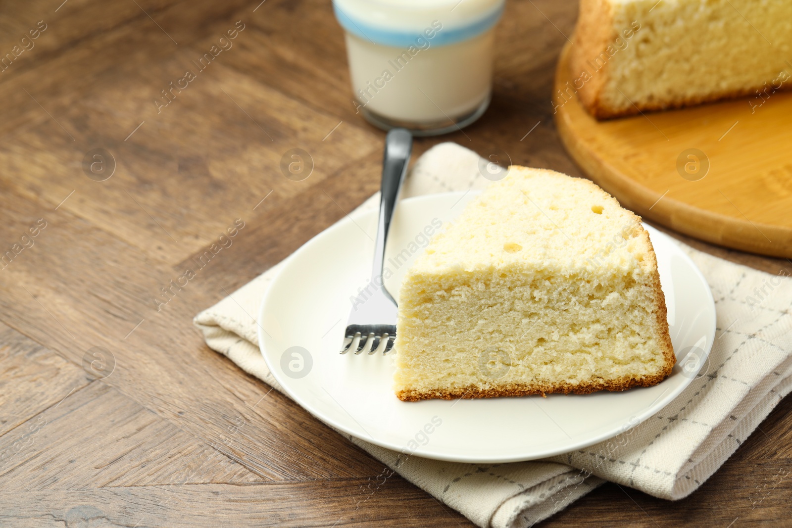 Photo of Piece of delicious sponge cake and fork on wooden table