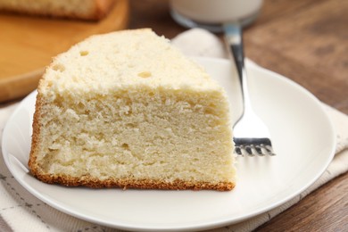 Photo of Piece of delicious sponge cake and fork on wooden table, closeup