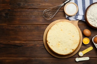 Photo of Delicious cut sponge cake, whisk and ingredients on wooden table, flat lay. Space for text