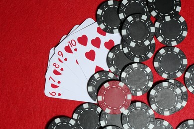 Photo of Playing cards and poker chips on red table, flat lay