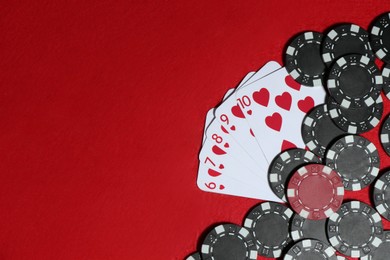 Photo of Playing cards and poker chips on red table, flat lay. Space for text