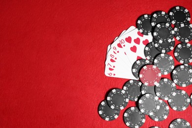 Photo of Playing cards and poker chips on red table, flat lay. Space for text