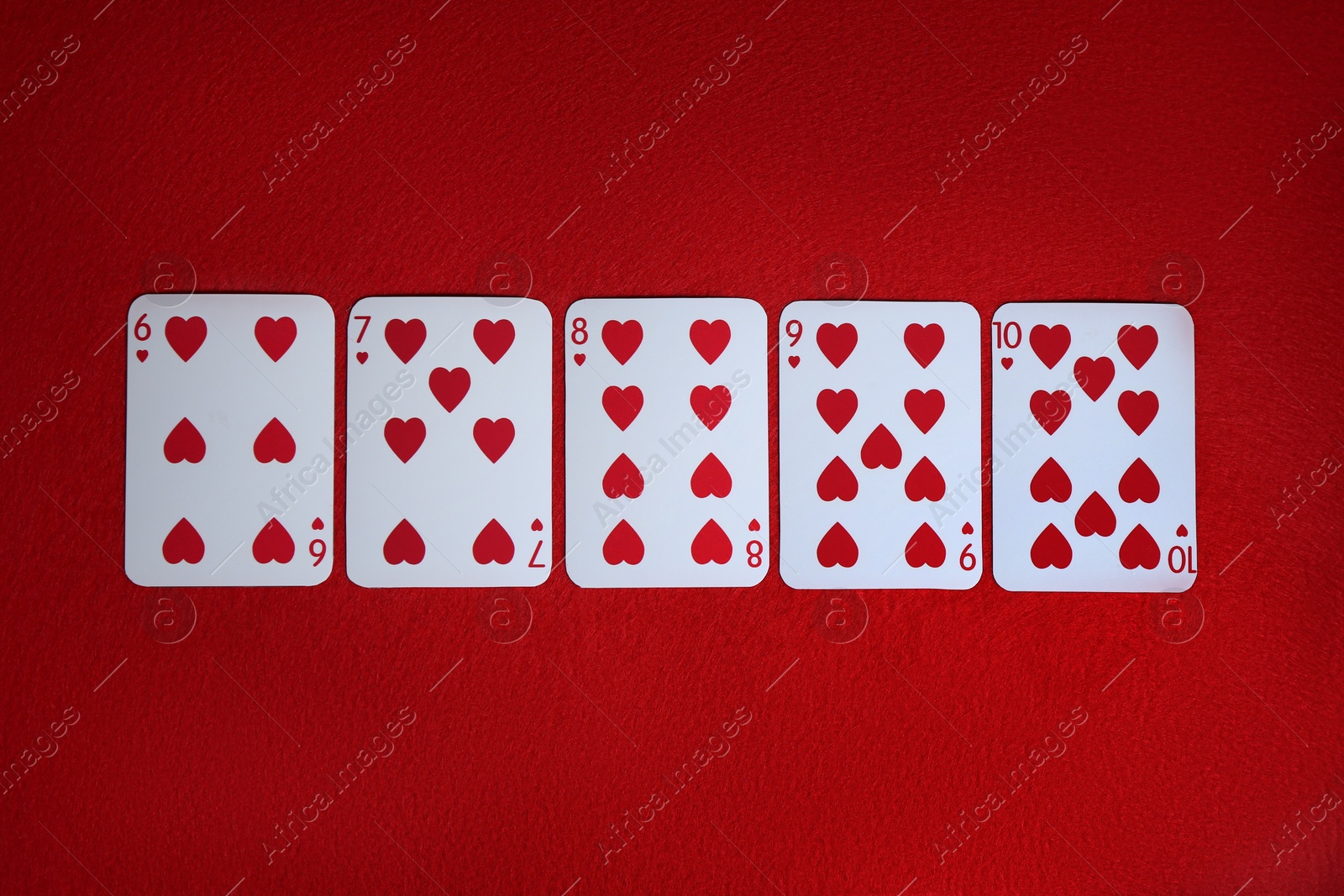 Photo of Poker game. Playing cards on red table, top view