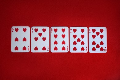 Photo of Poker game. Playing cards on red table, top view