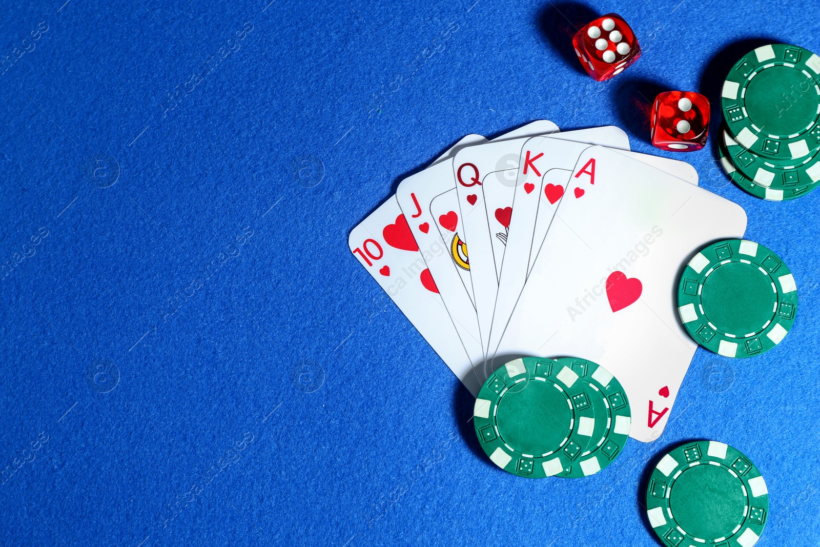 Photo of Playing cards, poker chips and cubes on blue table, flat lay. Space for text