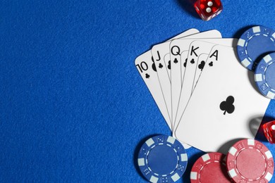 Playing cards, poker chips and cubes on blue table, flat lay. Space for text