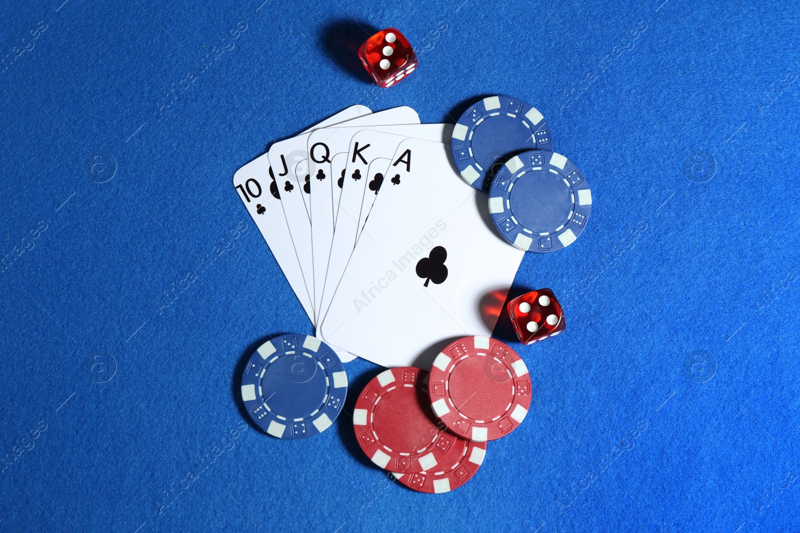 Photo of Playing cards, poker chips and cubes on blue table, flat lay