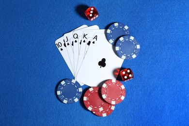 Photo of Playing cards, poker chips and cubes on blue table, flat lay