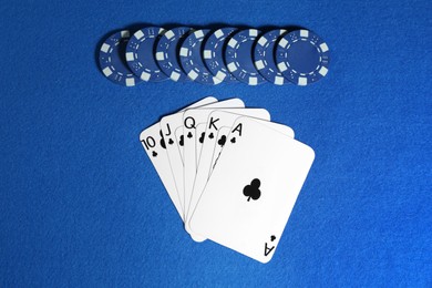 Photo of Playing cards and poker chips on blue table, flat lay