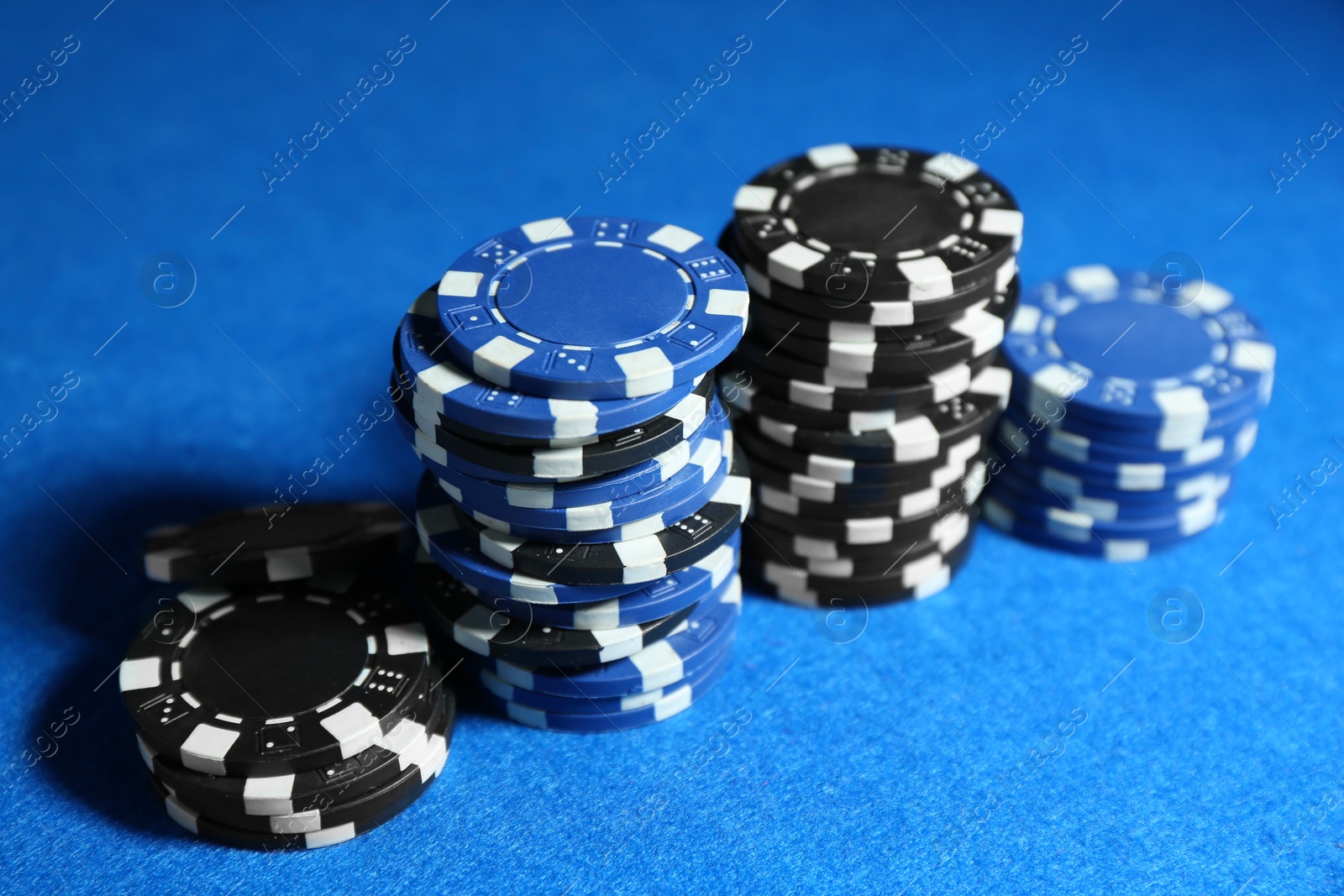 Photo of Poker game. Casino chips on blue table, closeup