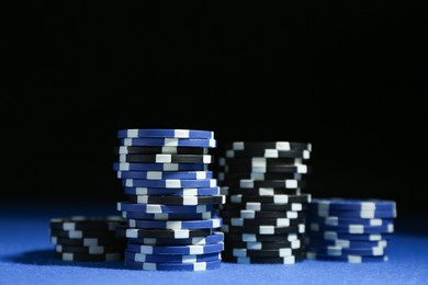 Photo of Poker game. Casino chips on blue table against dark background