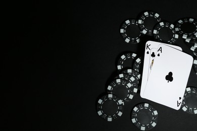 Photo of Playing cards and poker chips on black table, flat lay. Space for text