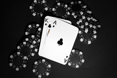 Photo of Playing cards and poker chips on black table, flat lay