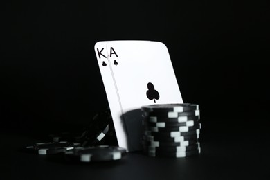 Photo of Playing cards and poker chips on black background