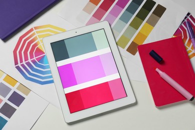 Photo of Designer's workplace with tablet, different palettes and stationery on white table, flat lay