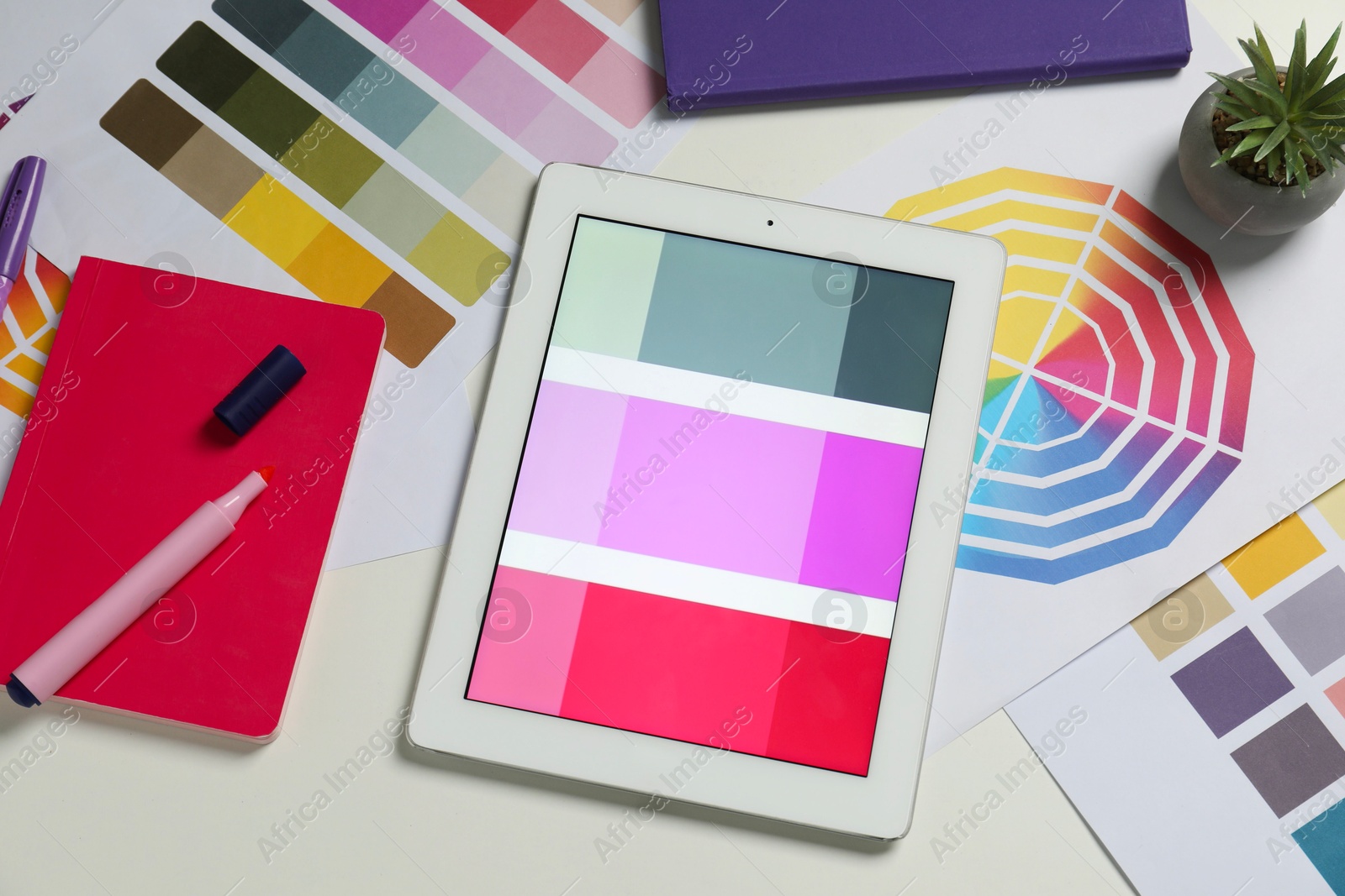 Photo of Designer's workplace with tablet, different palettes and stationery on white table, flat lay