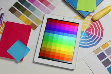 Photo of Designer's workplace with tablet, different palettes and stationery on white table, flat lay