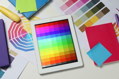 Photo of Designer's workplace with tablet, different palettes and stationery on white table, flat lay