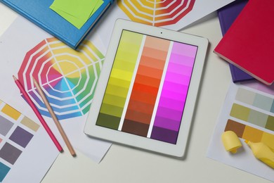 Photo of Designer's workplace with tablet, different palettes and stationery on white table, flat lay