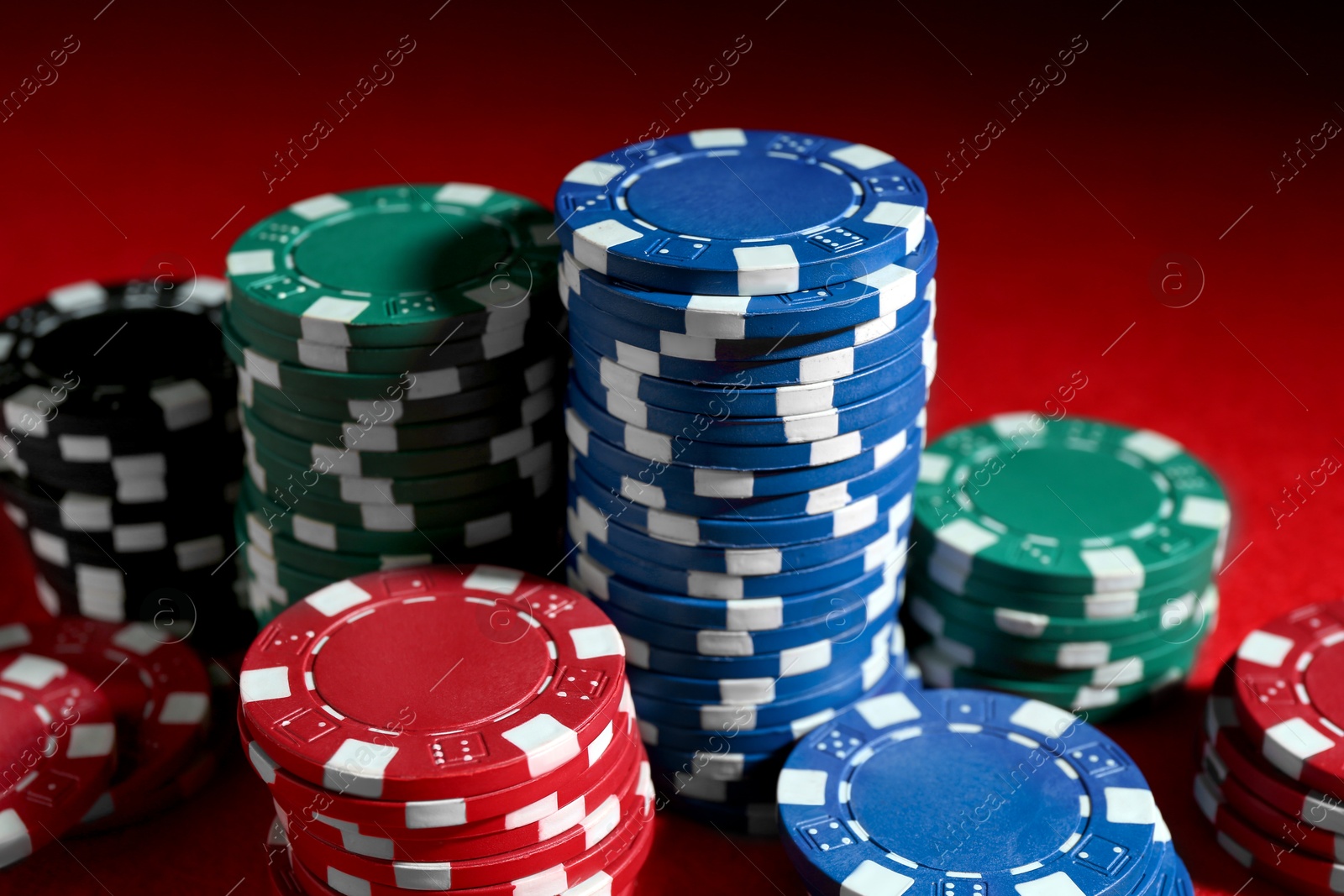 Photo of Poker game. Casino chips on red table, closeup