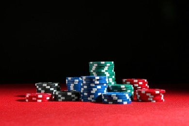 Photo of Poker game. Casino chips on red table against dark background