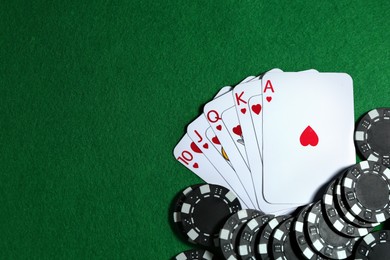 Photo of Playing cards and poker chips on green table, flat lay. Space for text