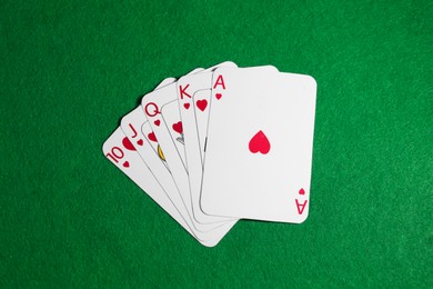 Photo of Poker game. Playing cards on green table, top view