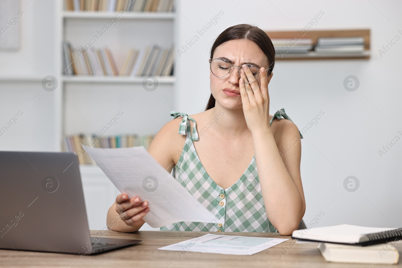 Photo of Tired student preparing for exam at table indoors