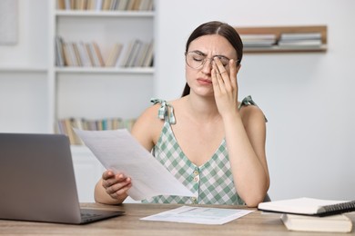 Tired student preparing for exam at table indoors