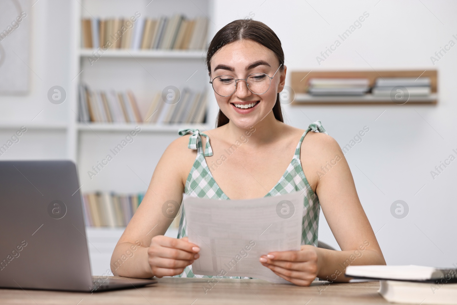 Photo of Happy student reading her good exam result at table indoors