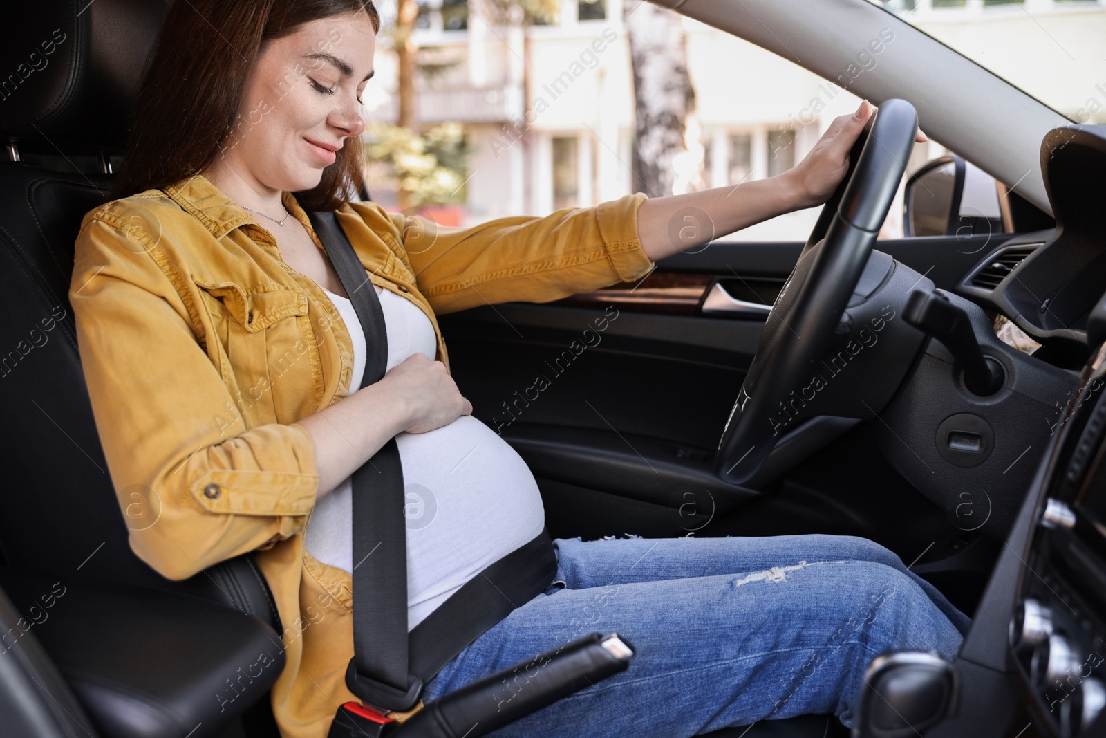 Photo of Pregnant woman with safety belt driving car