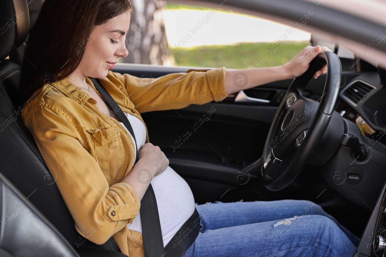 Photo of Pregnant woman with safety belt driving car