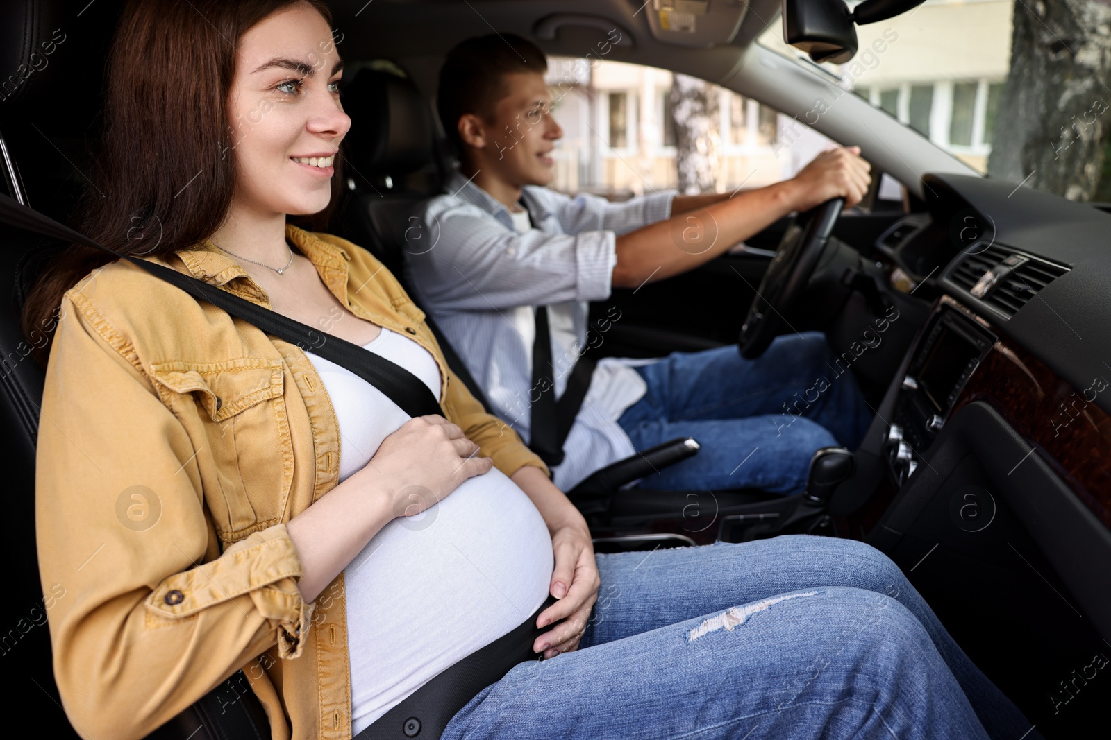 Photo of Smiling pregnant woman travelling with her husband by car