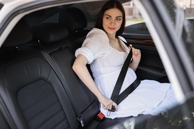 Photo of Pregnant woman fastening safety belt in car