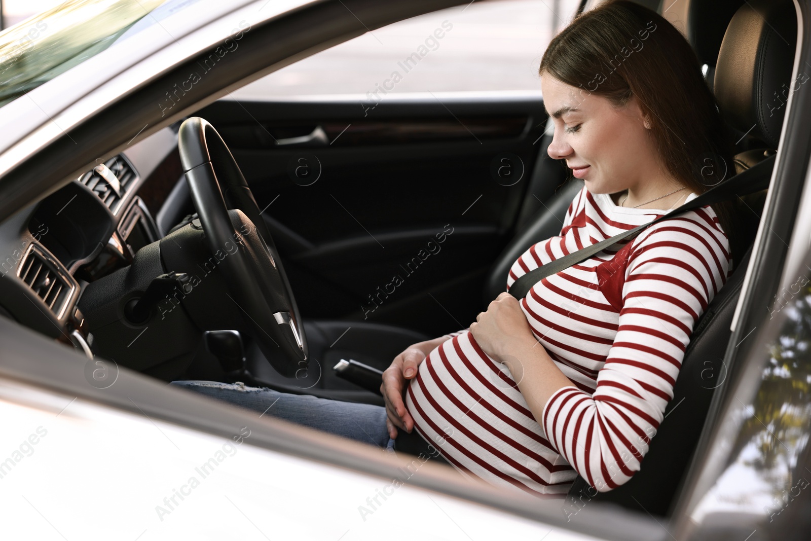 Photo of Pregnant woman with safety belt driving car, view from outside