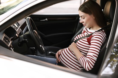 Photo of Pregnant woman with safety belt driving car, view from outside