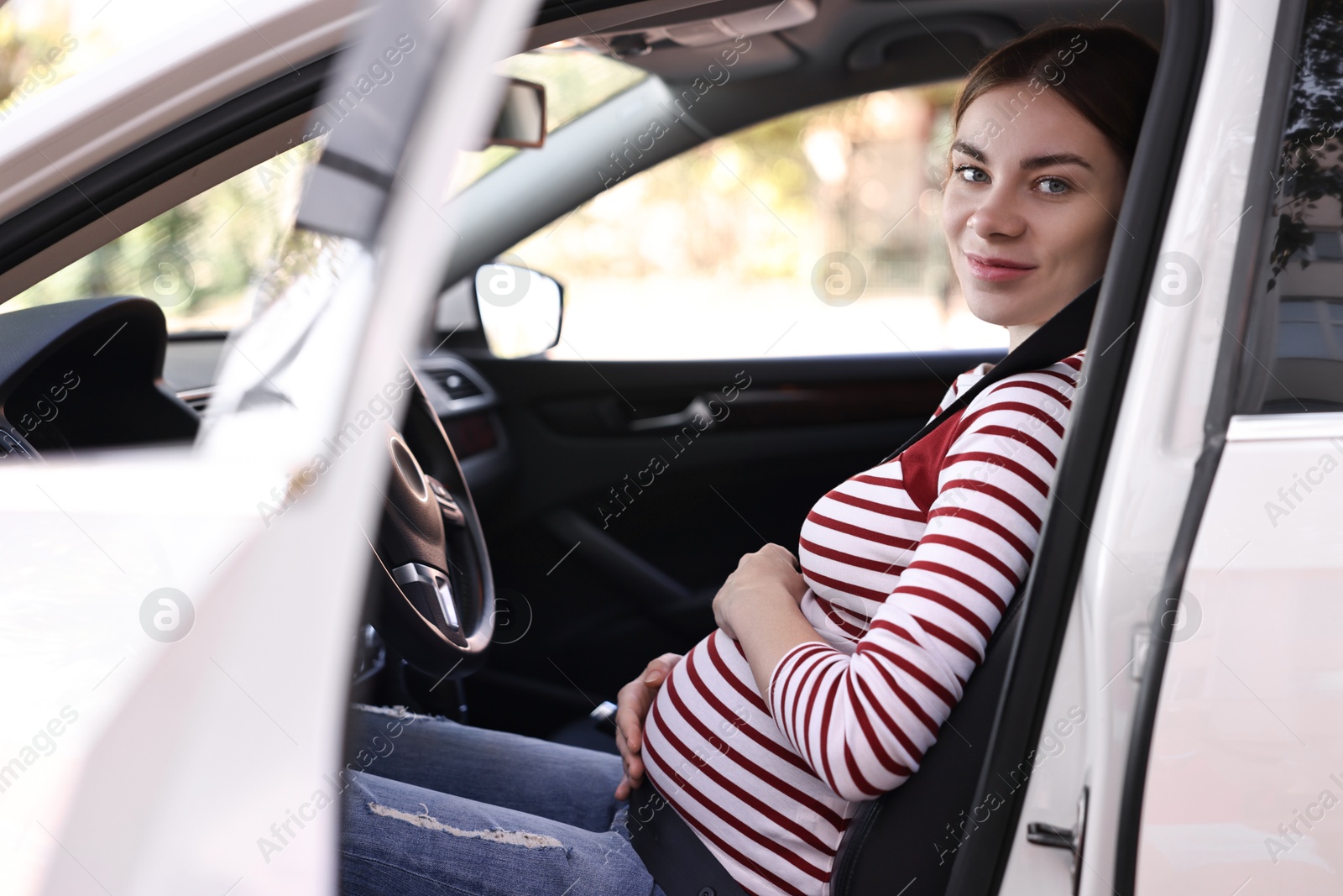 Photo of Pregnant woman with safety belt driving car, view from outside