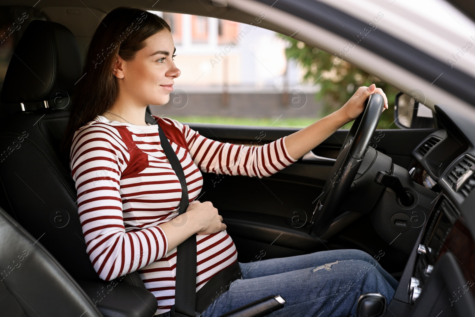 Photo of Pregnant woman with safety belt driving car